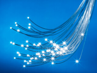 Bundle of optical fibers with lights in the ends. Blue background.