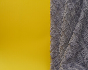 Artificial grey fur on yellow background.