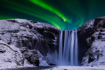 Skogafoss waterfall in the winter at night under the northern lights. Iceland