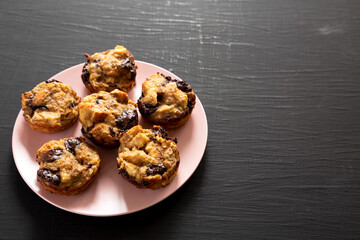 Homemade Chocolate Banana Bread Pudding on a pink plate on a black surface, low angle view. Copy space.