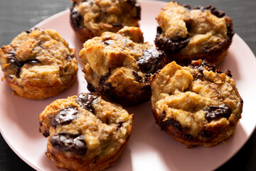 Homemade Chocolate Banana Bread Pudding on a pink plate on a black background, low angle view. Closeup.