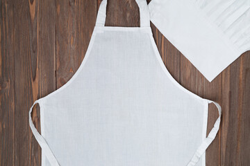 White apron template on wooden background, copy space. Kitchen, cooking clothing mockup