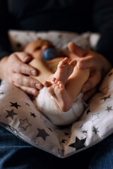 Feet of the newborn in the palms of the dad. Little baby fingers and daddy's hands. Small feet of a child. Baby feet. Baby feet close up. Newborn in the family.