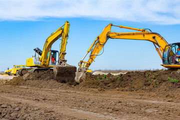 Fototapeta na wymiar Two big excavators are leveling ground on building site