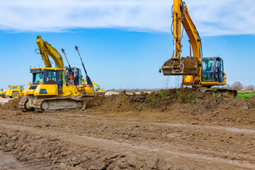 Two excavators and earthmover are leveling ground construction site