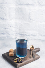 Thai blue tea anchan of buds klitoria Ternate in a glass cup, grey concrete background. Copy space.