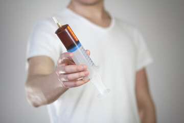 Man holds a large 160 ml syringe. Close up. Isolated on a gray background