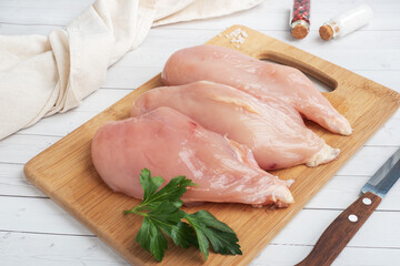 Raw chicken breast fillet, raw chicken meat on a cutting Board. White background, Copy space.