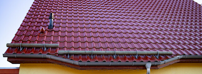 Tiled roof with segment of the snow holding structure, snow holder, round wooden trunk on iron...