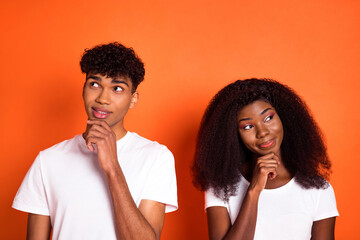 Photo of young happy thoughtful dreamy afro couple look copyspace thinking hold hand chin isolated on orange color background