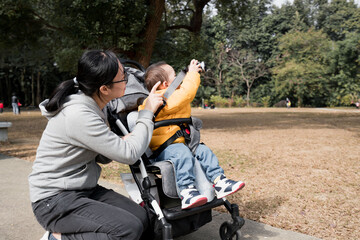 An Asian mother takes her son to the park to take pictures