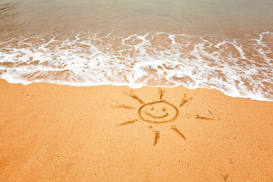 Smiling sun - drawing on the sand on a tropical beach