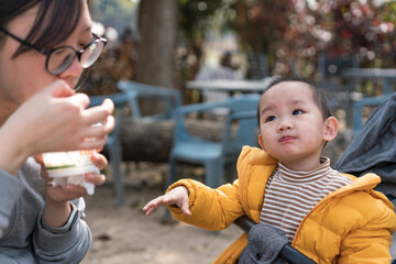 An Asian mother takes her son to the park to share food