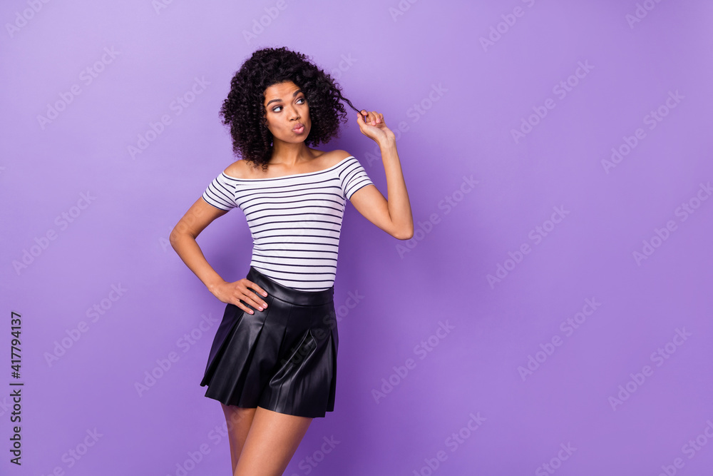 Poster portrait of pretty dark skin girl hand on waist fingers play with hair look empty space isolated on 