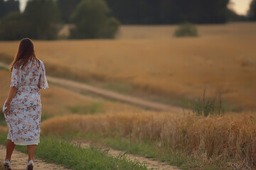 woman walks through a wheat field, in summer, a view from the back without a face, leaves, separation