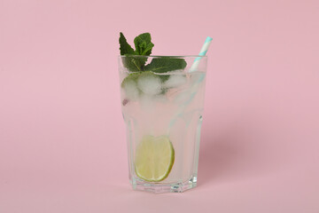 Glass of mojito cocktail on pink background