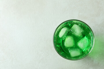 Glass of green soda on white textured background