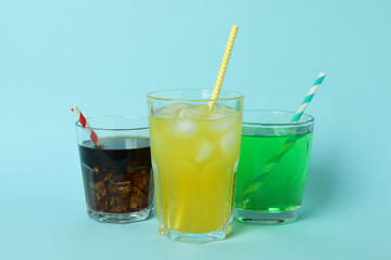 Glasses of different soda on blue background