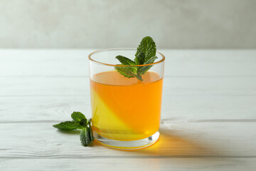 Glass of orange jelly with mint on white wooden table