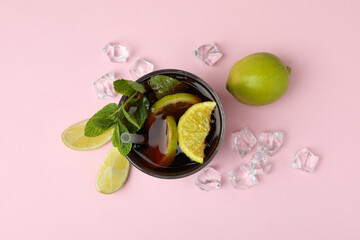 Glass of Cuba Libre cocktail on pink background