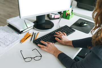 Adult woman middle aged woman with curly hair working on computer in bright modern office