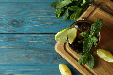 Board with glass of Cuba Libre on wooden background