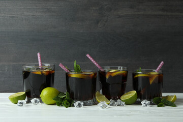 Glasses of Cuba Libre on wooden table against dark background