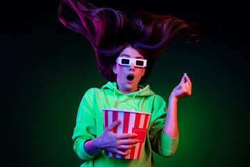 Photo of funky scared young woman dressed green pullover visiting cinema eating pop corn isolated vivid vibrant dark abstract background