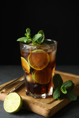Board with glass of Cuba Libre against dark background