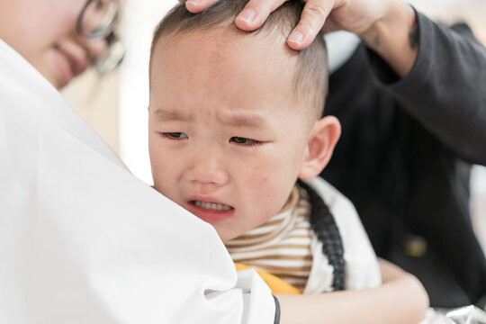 Asian mothers with their sons in their arms are having their hair cut