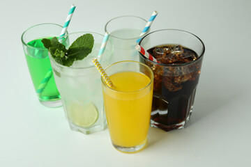 Glasses of different soda on white background