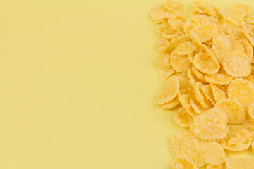 Pile of yellow cornflakes on yellow  background