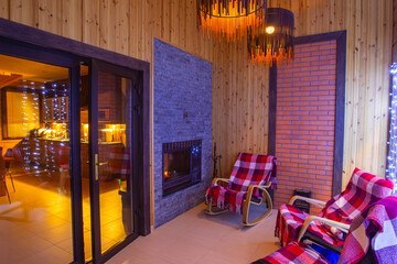 Interior of hotel. Lounge with fireplace. Small room in a country hotel. Several rocking chairs in a small room. Concept - rest in a country hotel. Glass door leading to dining room.