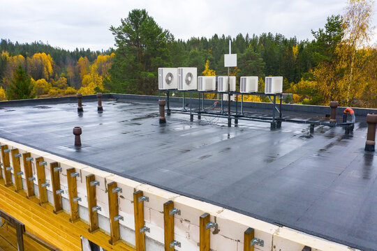 Lots of rooftop air conditioning units. Coniferous forest in background. Concept - installation of a ventilation system. Installation of air conditioning systems. Conditioners for industrial premises