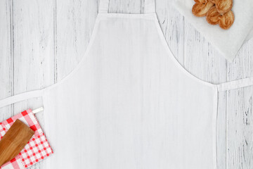 White apron template on wooden table with cookies, copy space. Kitchen, cooking clothing mockup