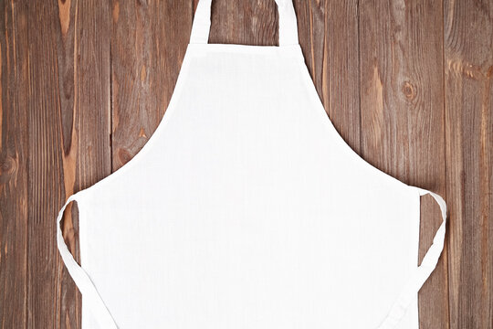 Blank white apron template on wooden background, copy space. Kitchen, cooking clothing mockup