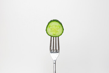Photo of a fresh cucumber on a fork isolated on a white background, part of a series.