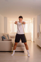 Fototapeta na wymiar Young man exercising with an elastic band at home. Quarantine time.