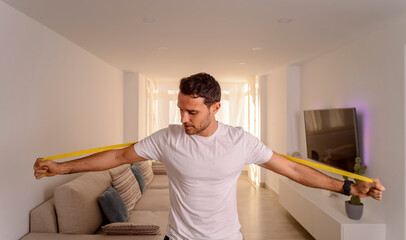 Portrait of handsome european man doing chest workout with elastic resistance bands at home