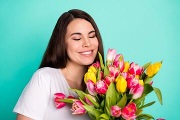 Photo of young attractive woman happy positive smile enjoy aroma spring flowers tulips isolated over turquoise color background