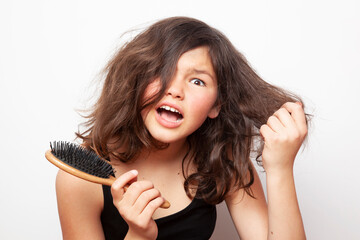 Teenager girl trying to comb her hair. The problem of teen