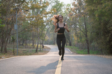 Young woman running outdoors in green park at lovely sunny summer day.