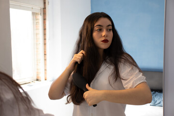 Woman combing her hair in front of the mirror.