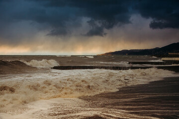 Storm waves near the shore on the beach. In the foreground, breakwaters.