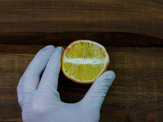 Ugly food trend. Spoiled yellow lemon half with red mold close up on wooden background. Moldy...