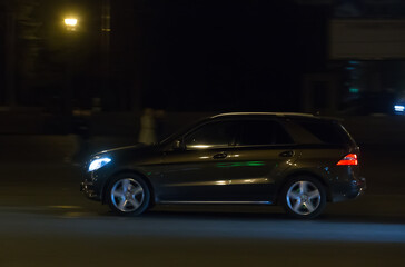 Fototapeta na wymiar SUV moves at night on city street