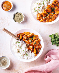 Chicken tikka masala and rice in white bowl on neutral table top