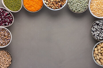 Different types of legumes in bowls, green and yellow peas, chickpeas and peanuts, colored beans and lentils, mung beans and beans, top view