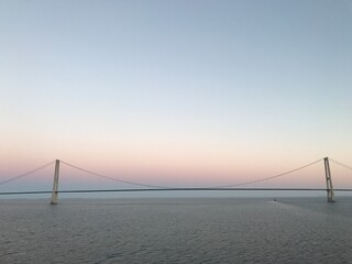 Obraz premium Brücke Hängebrücke Spannbeton Hohlkastenbrücke Storebæltsbroen Brückenzug in Dänemark in der Meerenge Großer Belt zwischen den Inseln Fünen und Seeland von einem Kreuzfahrtschiff bei Sonnenuntergang