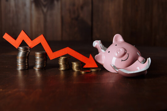 Piggy Bank and red arrow on coins stack. Investment and crisis concept.